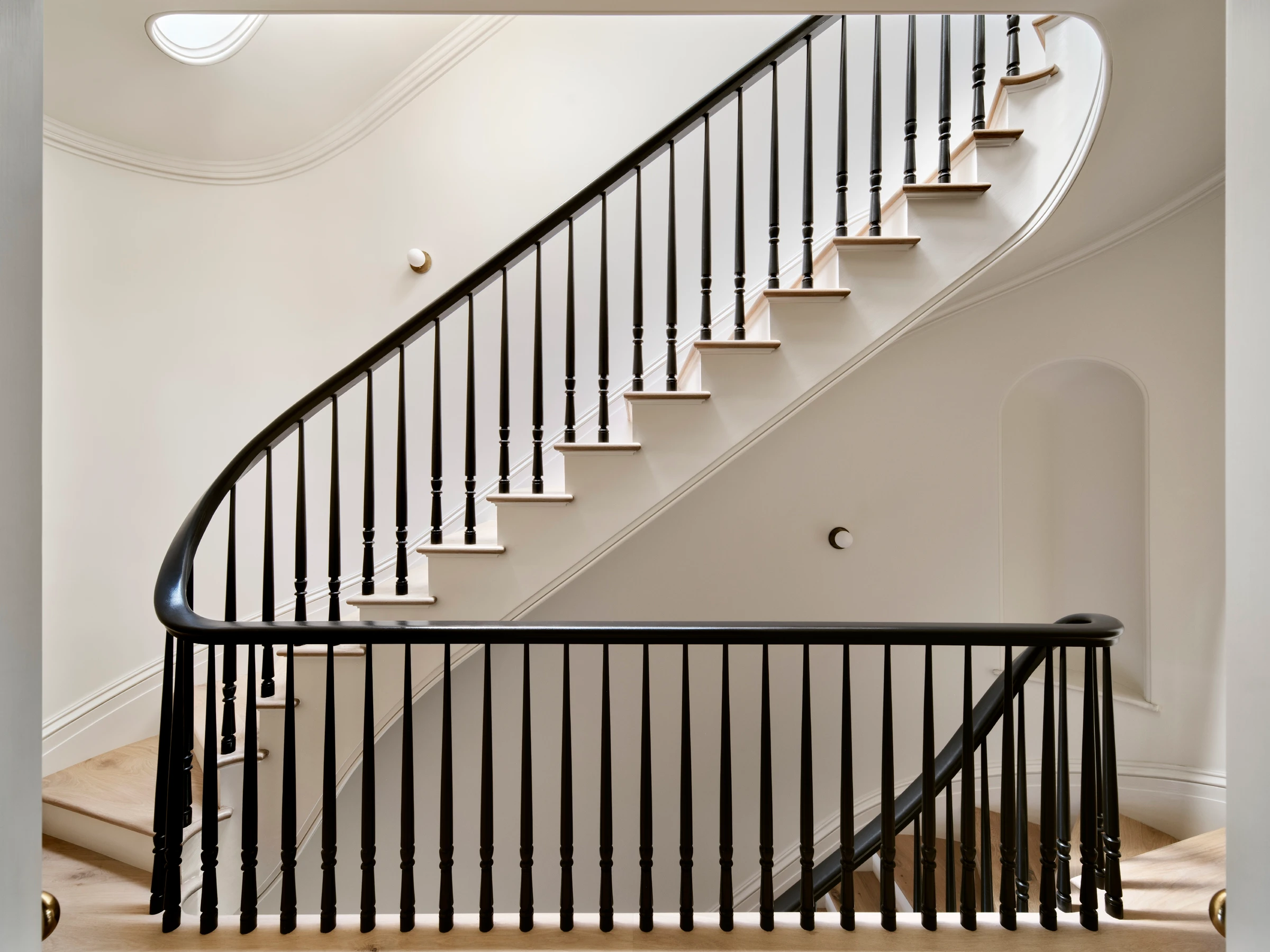 A winding stair with slim balusters and an oak handrail turns circulation into one of the house's clearest crafted elements.