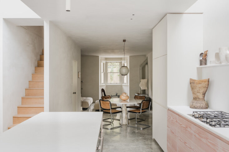 From the kitchen, cane-and-chrome Breuer Cesca dining chairs gather at a round table beyond a straight wood stair.