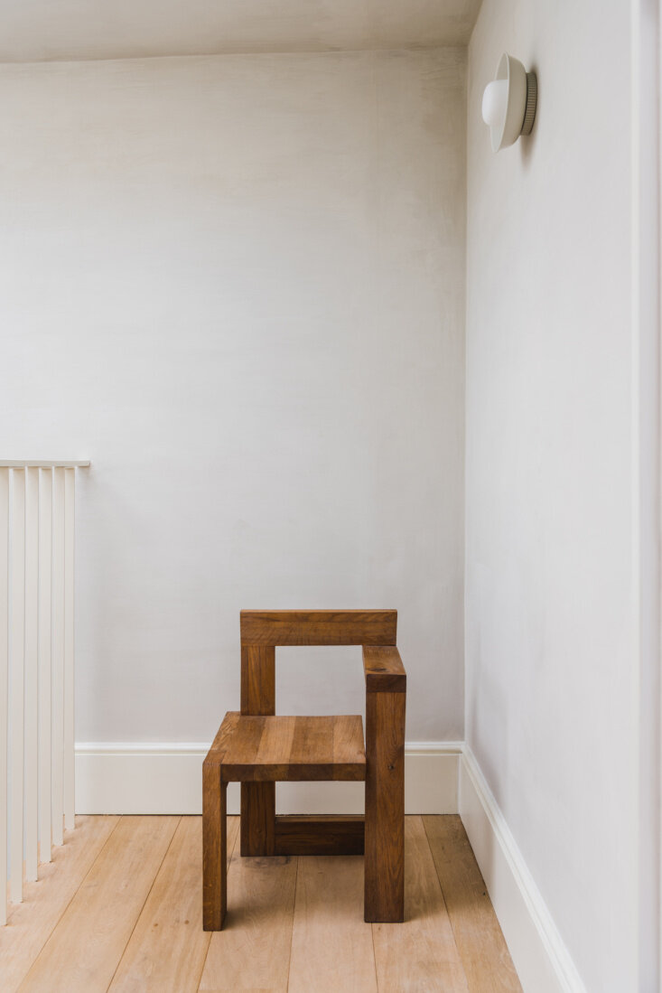 Top-floor landing places a Gerrit Rietveld Steltman chair against pale plaster walls and wide-plank wood flooring.