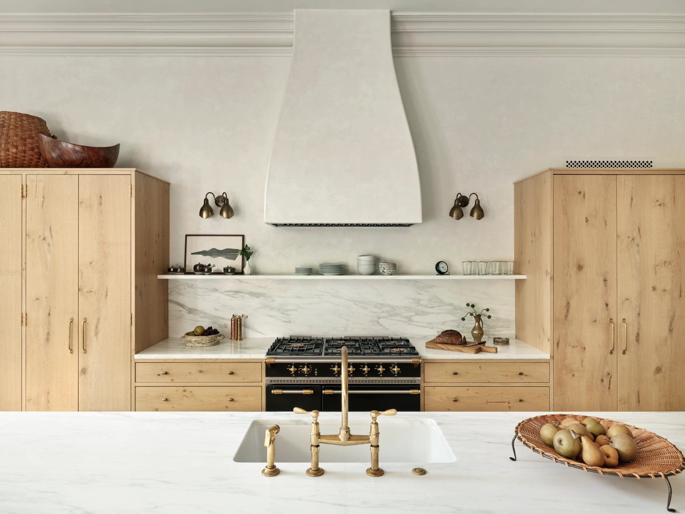 Flat-panel oak cabinetry wraps the kitchen wall, where pale counters and integrated appliances keep the room precise without feeling sterile.